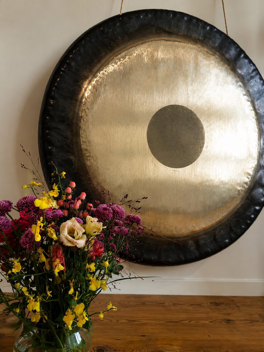 Gong an der Wand neben einem Strauß bunter Blumen